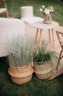 Doğal dokuma sepetlerinde bitkilerin bulunduğu açık salon, rahat ve davetkar bir atmosfer yaratıyor. Yumuşak mobilyalar ve küçük bir masa rahat bir açık hava toplanma alanı olduğunu gösteriyor.