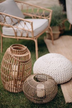 Dıştaki salon dekorunda rattan fenerler ve örgü pouf. Sıcak, bohem atmosfer