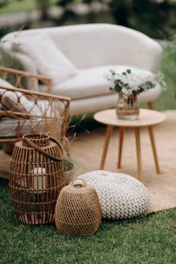 Dıştaki salon dekorunda rattan fenerler ve örgü pouf. Sıcak, bohem atmosfer