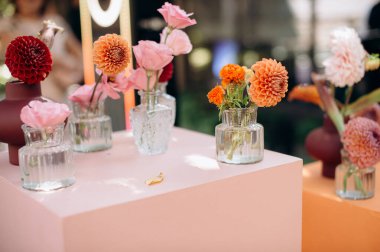 Pembe büfede küçük vazolarda portakallı yıldız çiçeklerinin yakın çekimi. Parlak, çiçek dekoru