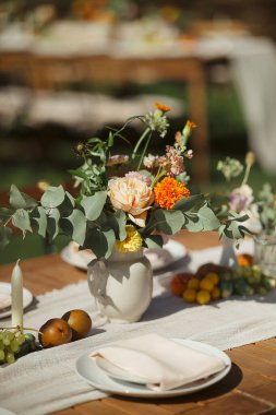 Portakal çiçeği ve okaliptüslü küçük cam vazo. Parlak, çiçekli masa dekoru.