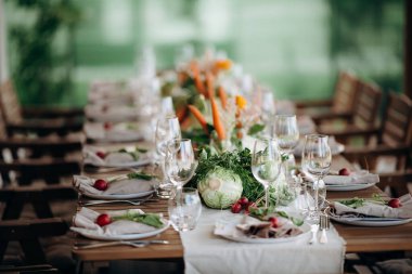 Ahşap bir yüzeye sebze aranjmanları ve çiçeklerle bir masa kurun.