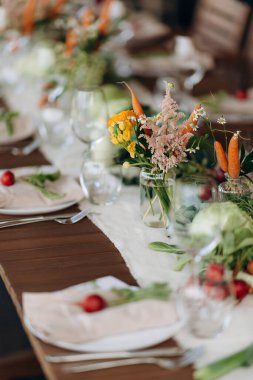 Ahşap bir yüzeye sebze aranjmanları ve çiçeklerle bir masa kurun.