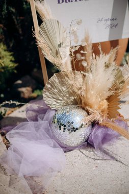 Kurumuş çiçekli disko topu ve taş bir yüzeyde mor tül.