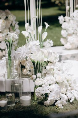 Açık havada zambaklar ve güllerle bembeyaz bir çiçek aranjmanı.