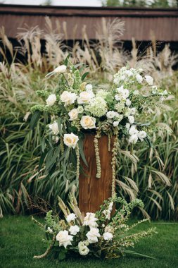 Açık havada gül ve okaliptüs içeren zarif beyaz çiçek aranjmanları.