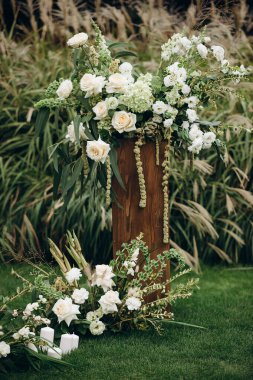 Açık havada gül ve okaliptüs içeren zarif beyaz çiçek aranjmanları.