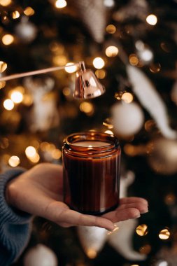 Mum söndürücüyle mumu söndüren genç bir kadının yakın çekimi. Huzurlu ve detaylı bir an mum bakım sürecini yakalıyor.