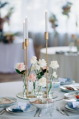 İnce, tek bir mum tutacağı içinde bir restorandaki ziyafet masasında yanan bir sürü ince beyaz mum. Etrafı çiçekler ve pastel tonlarla çevrili. Kutlama ya da ziyafet için şenlikli bir ortam yaratıyor.