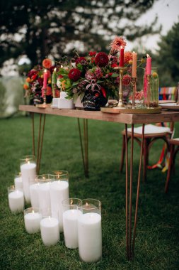Birçok sütun mum, düğün çifti başkanlığının temelindeki cam kürelerde yanıyor, canlı çiçeklerle süslenmiş, açık hava ziyafeti için şenlikli ve romantik bir ortam yaratıyor.
