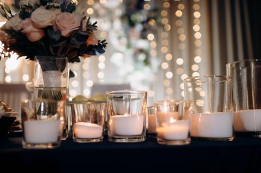 Mumlar çiçeklerle süslenmiş bir ziyafet masasında cam kürelerde yanıyor. Karanlıkta romantik ve zarif bir atmosfer yaratıyorlar.