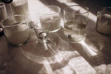 Güneş ışığı cam kürelerde sütun mumlarıyla parlıyor, masa örtüsünün üzerine ilginç desenler seriyor, sıcak ve büyüleyici bir atmosfer yaratıyor.