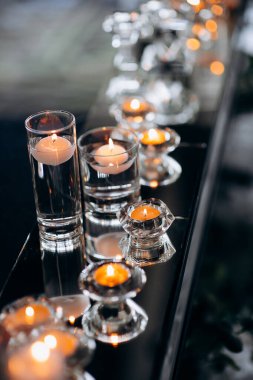 Cam kürelerde süzülen mumlar bir restoranda yeni evlilerin aynalı başkanlığında yanarak kutlama için zarif ve romantik bir ortam yaratıyor.