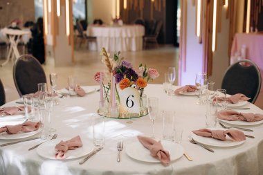 Restorandaki ziyafet masasının dekorunda uzun mumlar ve canlı sonbahar çiçekleri kutlama için sıcak ve şenlikli bir atmosfer yaratıyor.