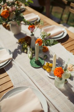 Restorandaki ziyafet masasının dekorunda uzun mumlar ve canlı sonbahar çiçekleri kutlama için sıcak ve şenlikli bir atmosfer yaratıyor.