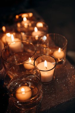 Mumlar karanlıkta cam kürelerde yanıyor. Mumların yumuşak parıltısıyla aydınlanıyor. Sıcak ve huzurlu bir atmosfer yaratıyor.