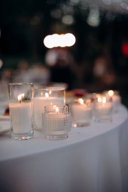 Mumlar karanlıkta cam kürelerde yanıyor. Mumların yumuşak parıltısıyla aydınlanıyor. Sıcak ve huzurlu bir atmosfer yaratıyor.