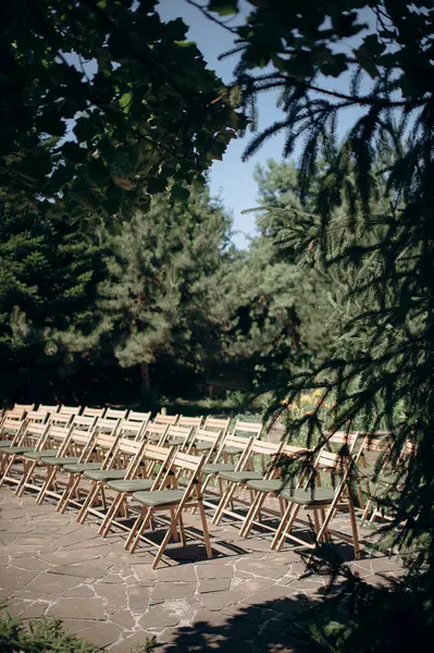 Yeşil yastıklı ahşap katlanır sandalyeler açık havada bir terasta durur.