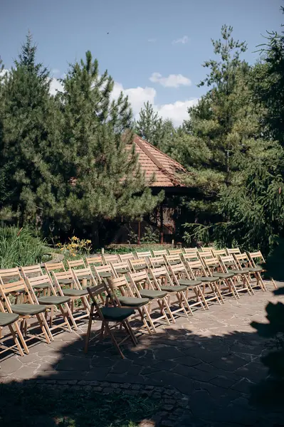 Yeşil yastıklı ahşap katlanır sandalyeler açık havada bir terasta durur.