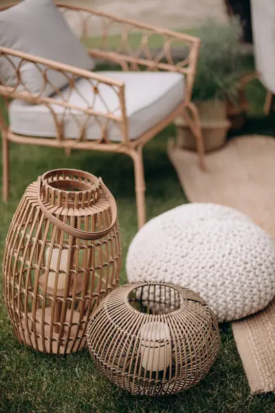 Dıştaki salon dekorunda rattan fenerler ve örgü pouf. Sıcak, bohem atmosfer