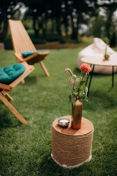 Yıldız çiçeği buketi ve halat sehpasında mum olan açık hava salonu.