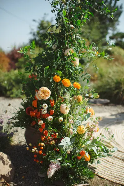 Bahçede güller ve kadife çiçeklerle süslenmiş zarif çiçek aranjmanları.