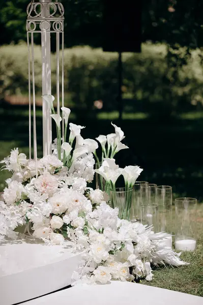 Açık havada zambaklar ve güllerle bembeyaz bir çiçek aranjmanı.