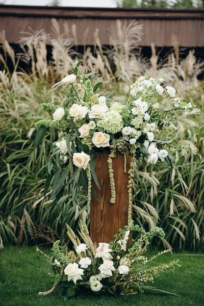 Açık havada gül ve okaliptüs içeren zarif beyaz çiçek aranjmanları.