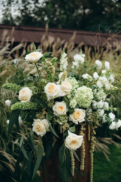 Açık havada gül ve okaliptüs içeren zarif beyaz çiçek aranjmanları.