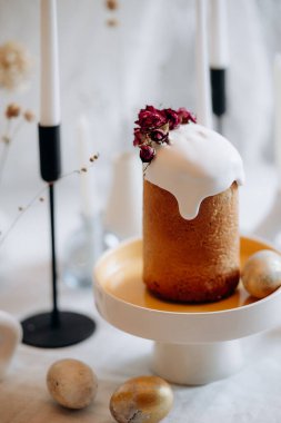 Beyaz kremalı Paskalya ekmeği ve süslenmiş bir masada mumlar ve boyanmış yumurtalarla kırmızı böğürtlen.