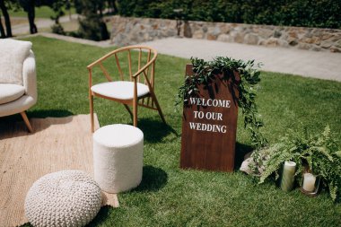 Hoş geldin tabelası ve yumuşak koltuklu rahat bir düğün salonu.