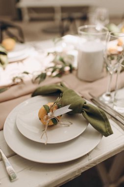 Yeşil peçeteli beyaz bir tabağın ve küçük bir portakalın yakın çekimi.