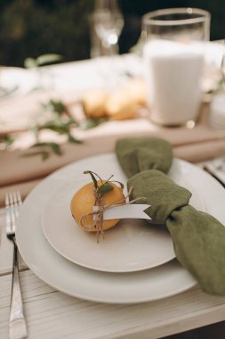 Yeşil peçeteli beyaz bir tabağın ve küçük bir portakalın yakın çekimi.