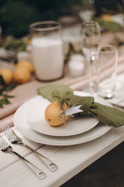 Yeşil peçeteli beyaz bir tabağın ve küçük bir portakalın yakın çekimi.