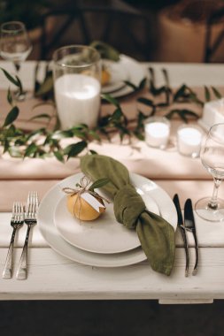 Yeşil peçeteli beyaz bir tabağın ve küçük bir portakalın yakın çekimi.