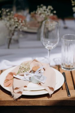 Okaliptüs yaprakları ve bej keten peçeteli şık bir açık hava sofrası.