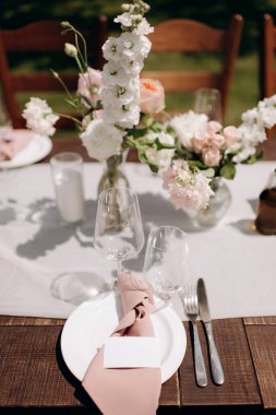 Okaliptüs yaprakları ve bej keten peçeteli şık bir açık hava sofrası.