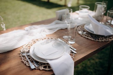 Küçük vazolarda beyaz çiçekler olan şık bir açık hava masası.