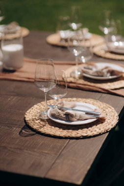 Koyu kahverengi ahşap bir masa üzerinde dokuma minderi olan şık bir açık hava masası.