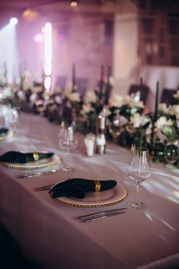 Sahne ışıkları altında altın ve yeşil renkli şık bir ziyafet masası.