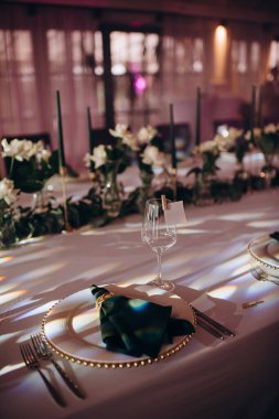 Sahne ışıkları altında altın ve yeşil renkli şık bir ziyafet masası.