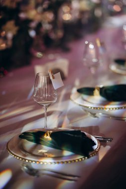 Yansıtıcı yüzeyde altın ve yeşil renkli zarif bir kapalı masa ayarı.