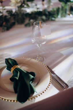 Sahne ışıkları altında altın ve yeşil renkli şık bir ziyafet masası.