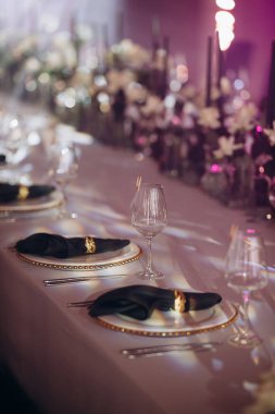 Sahne ışıkları altında altın ve yeşil renkli şık bir ziyafet masası.