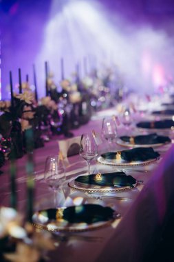 Sahne ışıkları altında altın ve yeşil renkli şık bir ziyafet masası.