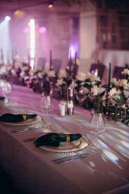 Sahne ışıkları altında altın ve yeşil renkli şık bir ziyafet masası.