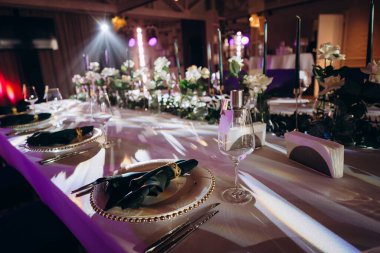 Sahne ışıkları altında altın ve yeşil renkli şık bir ziyafet masası.