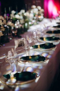Sahne ışıkları altında altın ve yeşil renkli şık bir ziyafet masası.