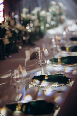 Sahne ışıkları altında altın ve yeşil renkli şık bir ziyafet masası.