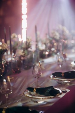 Sahne ışıkları altında altın ve yeşil renkli şık bir ziyafet masası.